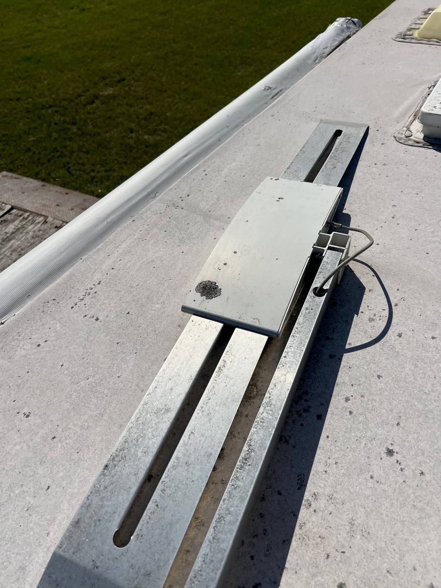 Before: RV roof with a roof-mounted antenna on its rails, the membrane dingy and spotted with black stains