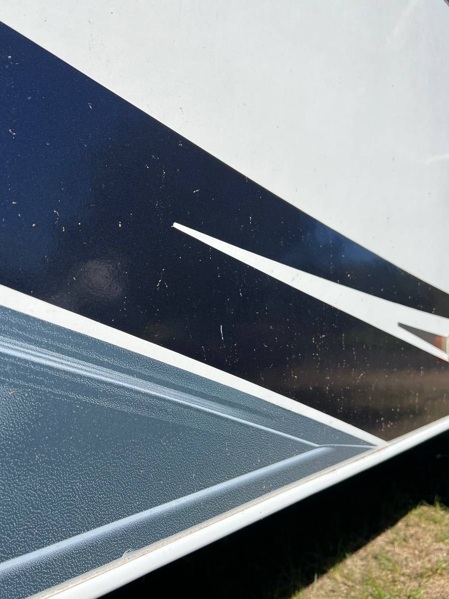 Before: close-up of a black graphic stripe on an RV sidewall, specked with dirt
