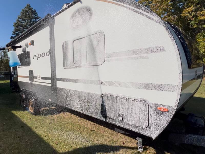 Foam cannon covering the side of a travel trailer in soap
